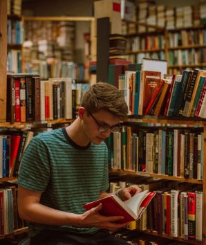 Student stood reading a book in the library