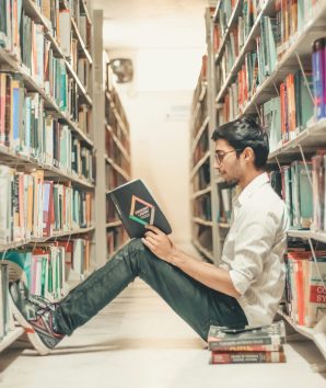 Student sat on the library floor reading a book