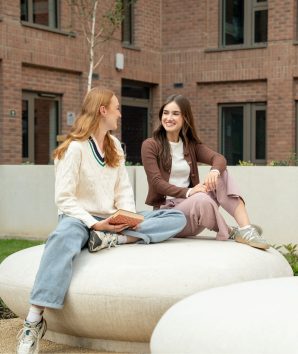 Students socialising outdoors, sat on seating